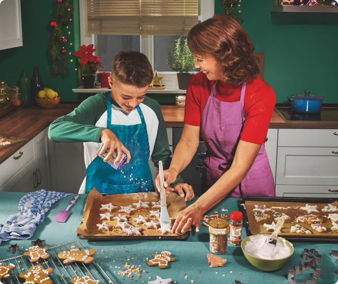 Eine Mutter dekoriert in der Küche mit ihrem Sohn Weihnachtsplätzchen.